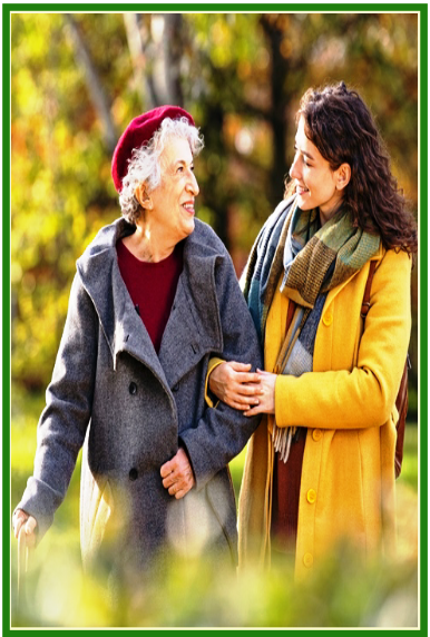 Eine Alltagsbetreuerin und eine ältere Dame, die an einem Stock geht, unternehmen gemeinsam einen Spaziergang durch den Park. Die Betreuerin hält die Dame fest und unterstützt sie, aber es sieht eher aus wie ein gemeinsamer Ausflug von zwei Menschen, die sich nahe stehen, als wie eine Betreuungssituation. Die beiden Frauen teilen einen Moment der Verbundenheit und des Vertrauens, während sie durch den Park gehen.